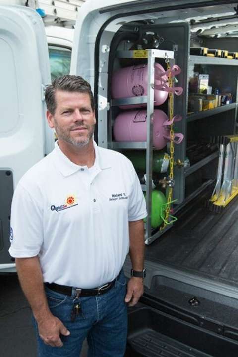 air technician standing outside of his truck with tool performing Commercial Air Condition repairs in Deerfield Beach