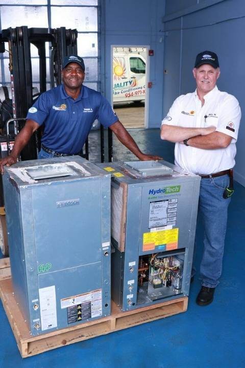 Two technicians in front of an Air Conditioner unit